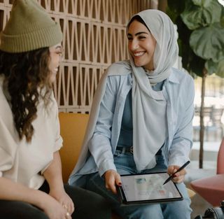 A tutor smiling while working through a lesson on a tablet with a student.